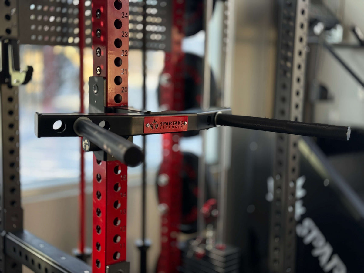 Spartaks Strength Y-Shape One Piece Dip Station (Adjustable Width) attached to a squat rack for strength training.